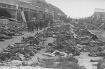 American soldiers walk past corpses that have been laid out in rows at the newly liberated Nordhausen concentration camp.