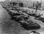 American troops stand amidst rows of corpses that were removed from the central barracks (Boelke Kaserne) of the Nordhausen concentration camp.