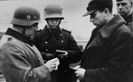 German police or soldiers check the identification papers of a Jew in the streets of Krakow.