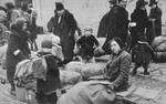 Jews assembled on the street with their bundles.

It is not clear whether they are waiting to be resettled in the Krakow ghetto, or to be taken to the trains during a deportation action in the ghetto.