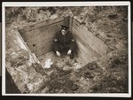 A Dutch policeman crouches inside a small bunker that served as a hiding place for Dutch Jews in the Eibergen region in 1942-1943.