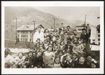 Children in the in the Morgins refugee camp school pose with their teacher by a fence.