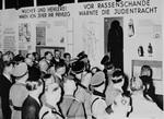 Nazi officials in attendance at the opening of "The Eternal Jew" exhibition in Munich, view a segment entitled, "Jewish dress was a warning against racial defilement."  To the left is a segment entitled, "Usury and the fencing of goods were always their privilege."