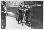 A Nazi forces a German Jew to take a broom and sweep the pavement.