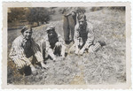 Three Buchenwald survivors pose on the grass in their uniforms after liberation.