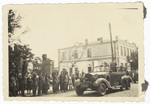 Czech civilians stand and greet Hitler as his motocade rolls by.