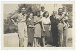 A Jewish family poses with American soldiers and the mayor of the town after liberation.