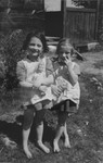 Twin sisters Sylvia and Anna Morgenstern pose with their dolls while living in hiding in occupied Poland.