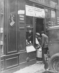 A Jewish shopkeeper helps a customer in the doorway of his grocery store in the Jewish quarter in Paris.