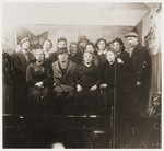 Group portrait of Jewish men and women in front of a stage set at a Purim celebration in the Zabno ghetto.