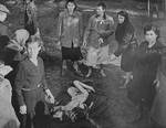 Women survivors in Bergen-Belsen prepare to remove the corpse of the woman at their feet.