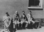 Survivors sit on a bench outside of a camp building in Bergen-Belsen.