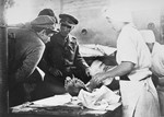 British physicians examines a Typhus patient who is being bathed by nurses.