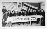 Members of the Zionist group Partizanim-Hayyalim-Halutzim meet in the Zeilsheim displaced persons' camp held in a room decorated with flags and posters.