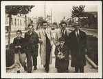 Mosa (Moshe) Mandil, Gavra, and Refik Veseli walk along the streets of Tirana with friends on liberation day.