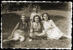 Four Jewish youth who returned to Bedzin after the war, pose outside seated on the grass.