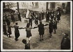 Zionist youth dance the hora around a flag [perhaps prior to their leaving for Palestine aboard the Champollion].