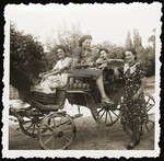 Miriam Schwarcz (holding her nephew), poses in an open carriage with her sister Lilly (left) and other relatives.
