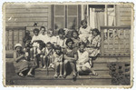 A large group of Lithuanian Jews pose on the steps of a wooden building in a summer colony in Palanga.