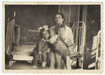Portrait of a Romanian Jewish mother and her two children sitting on a bed.