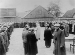 Jewish men are assembled in a large courtyard or public square in Raciaz.