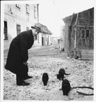 Ernest Kovacs (uncle of the donor) stands nexts to a group of cats on a street in Galanta.