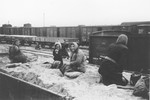 A group of Jewish women rest on top of a pile of dirt on a rail car where they have been shoveling.