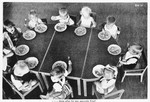 German propaganda picture showing young German children sitting around a table and eating a meal.
