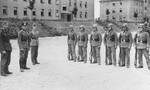Members of Police Battalion 323 and probably Lithuanian auxiliaries stand at attention in a courtyard in front of the student dormatories of the University of Kaunas.
