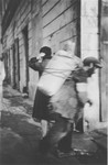 A porter carries a large bundle on his back in an unidentified ghetto in Poland.