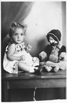Studio portrait of a young Jewish child seated next to a doll.