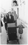 A young Jewish child walks along a street with her nanny and baby sister (in a carriage) in Osijek, Croatia.