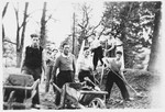 A group of Jewish refugee youth work outside with hoes, rakes and wheelbarrows at the Masgelier children's home.