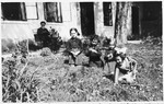 Four young Jewish girls play in the garden while their grandfather looks on.