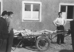 Survivors stand next to a cart loaded with corpses outside the crematoria in the newly liberated Buchenwald concentration camp.