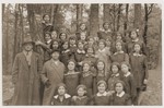 Group portrait of students and teachers of the Yehudia Jewish gymnasium for girls during an outing to a forest.