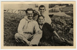 Close-up portrait of a man and three boys sitting in a field in Drohobycz.