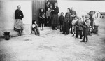 A group of women and children stand in the doorway of a barracks, likely in the Rivesaltes internment camp in France.