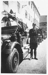 Leo Holzer, chief of the Theresienstadt fire brigade, poses next to a fire truck marked Terezin on the hood.