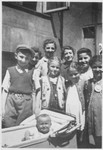 Group portrait of Jewish children in the Warsaw ghetto posing around a baby in a carriage.