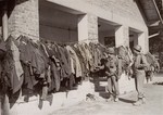 Two American soldiers examine disinfected prisoner uniforms in Dachau.