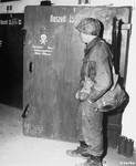 A soldier from the U.S. 7th Army examines the door to a gas chamber in the Dachau concentration camp.