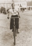 A young Jewish woman rides a bicycle through a public square in Lancut, Poland.