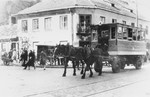A horse-drawn streetcar runs down a street in the Warsaw ghetto.