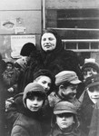 A woman stands behind a group of boys on a street in the Warsaw ghetto.