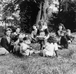 A group of young children sit in a circle on the grass outside the OSE Home in Draveil.
