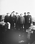 Members of Kibbutz Buchenwald pose next to a memorial or gravemarker at a cemetery.
