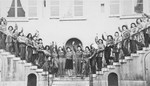 Young Jewish women living at the Le Tremplin children's home pose waving on the front staircase.
