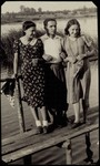 Three young people stand on a wooden bridge in Eisiskes.