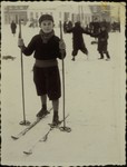 A Jewish child poses on skis on a snow-covered street in Eisiskes.